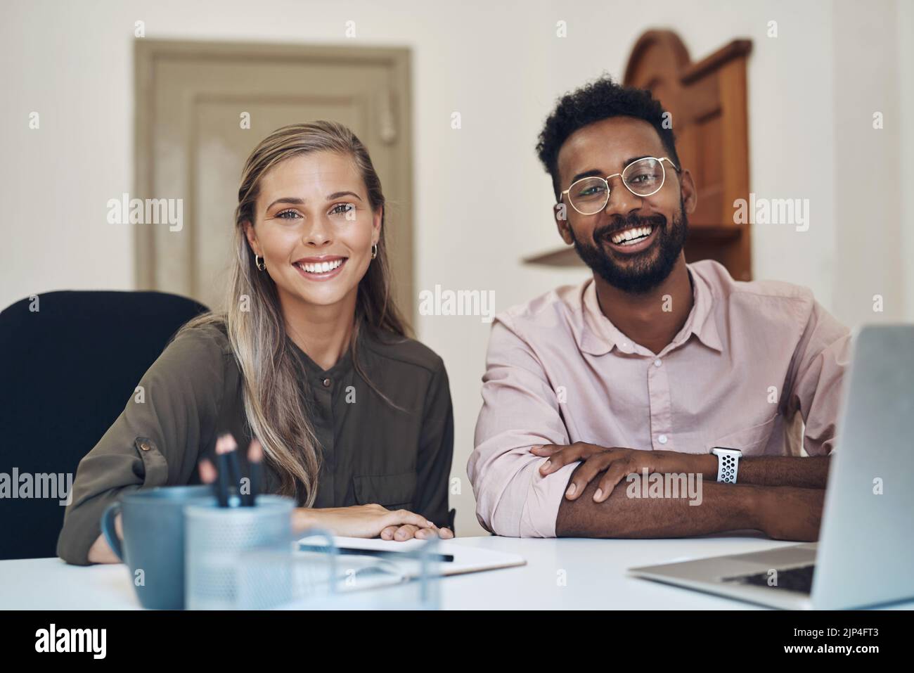 Heureux divers employés travaillant ensemble sur un projet assis à une table de bureau satisfaits du partenariat. Portrait de jeunes collègues avec un Banque D'Images