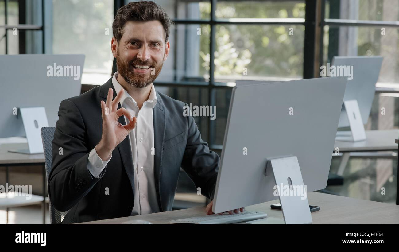 Joyeux succès gai barbu 40s homme d'affaires caucasien adulte 30s homme d'affaires Manager travailleur travaillant avec l'ordinateur dans le bureau sourire regardant dans l'appareil photo avec Banque D'Images