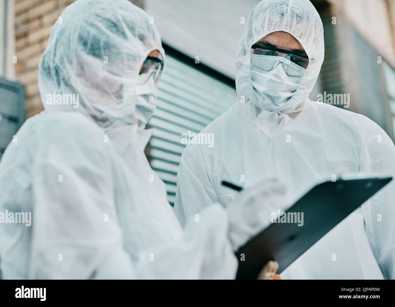 Les travailleurs de la santé portant des combinaisons de protection contre les risques rédigeant un rapport médical sur les cas de covid ou des statistiques. Les premiers intervenants remplissent un formulaire après Banque D'Images