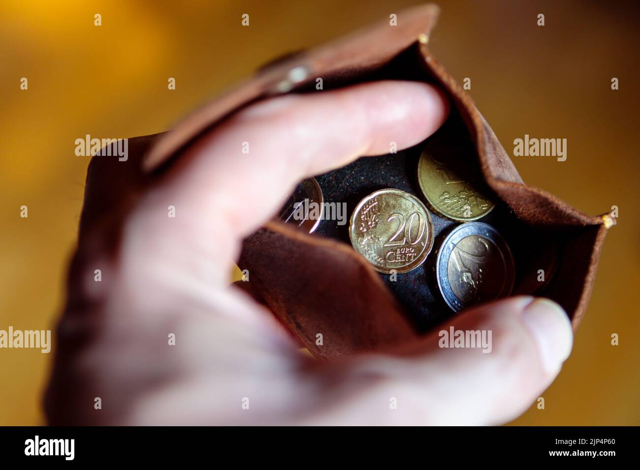 Un portefeuille en cuir avec des pièces en euros dans une main de homme. Banque D'Images