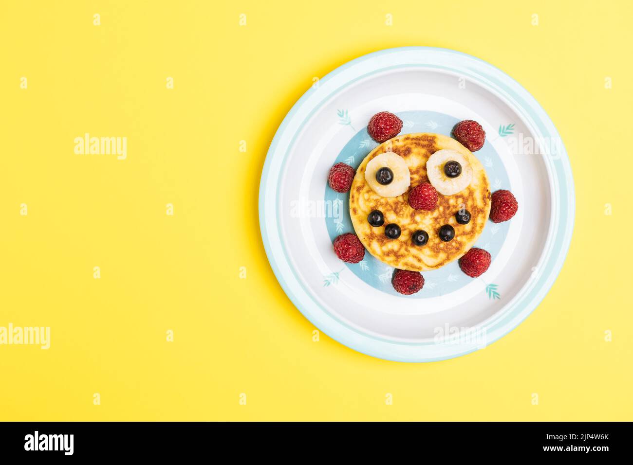 Crêpes américaines décorées comme sourire et visages heureux avec framboises, bleuets et bananes. Nourriture pour enfants, ludique et créative. Vue de dessus. Banque D'Images