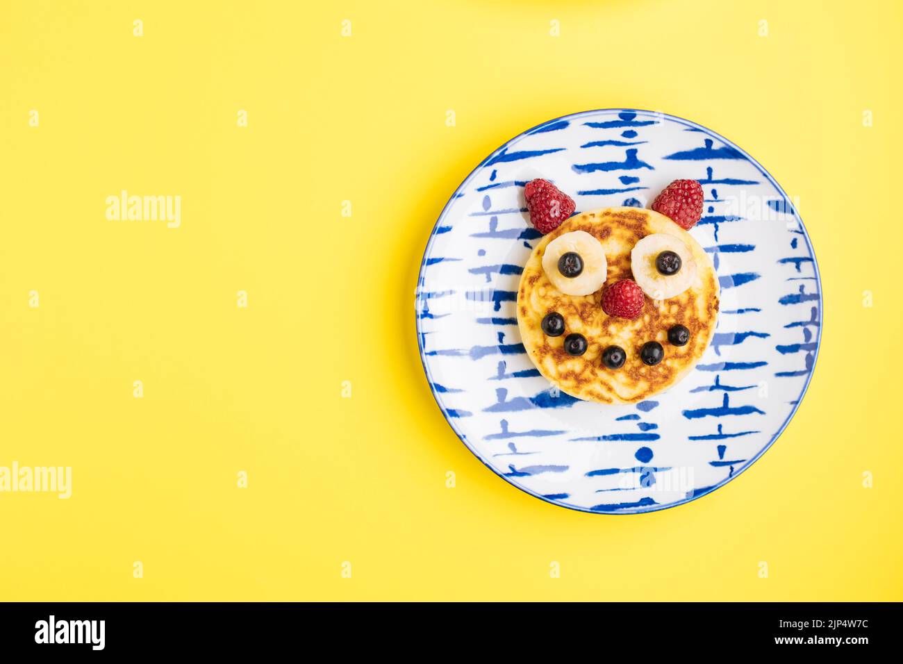 Crêpes américaines décorées comme sourire et visages heureux avec framboises, bleuets et bananes. Nourriture pour enfants, ludique et créative. Vue de dessus. Banque D'Images