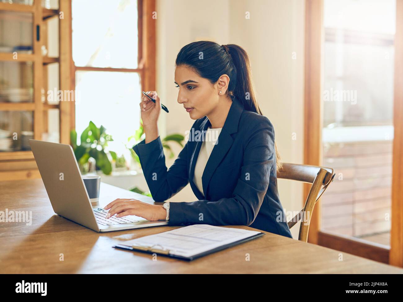 Un peu de travail fait à la maison. Une jeune femme d'affaires travaillant sur un ordinateur portable dans son bureau à domicile. Banque D'Images