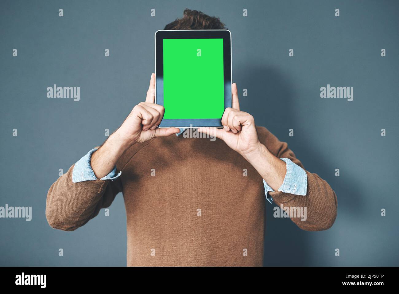 Tablette avec écran vert, touche de couleur et espace de copie maintenu par l'homme sur fond gris. Technologie et publicité ou marketing d'une entreprise numérique Banque D'Images