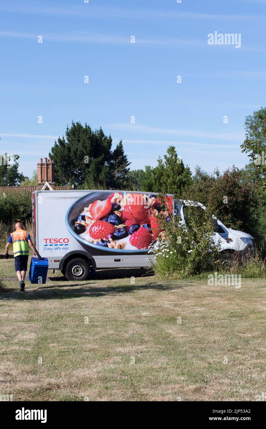 Chauffeur retournant à la camionnette avec plateau d'emty, camion de livraison à domicile Tesco, livraison de nourriture et de boissons au supermarché dans la région rurale de Suffolk, Angleterre, Royaume-Uni Banque D'Images