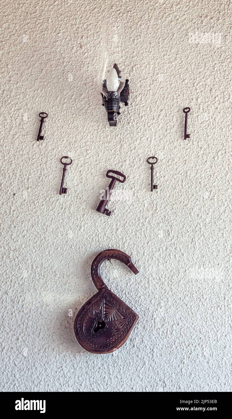 Style et concept nostalgiques. Une ancienne serrure en bois et de vieilles grandes clés sont sur le mur blanc. Vertical et gros plan. Banque D'Images