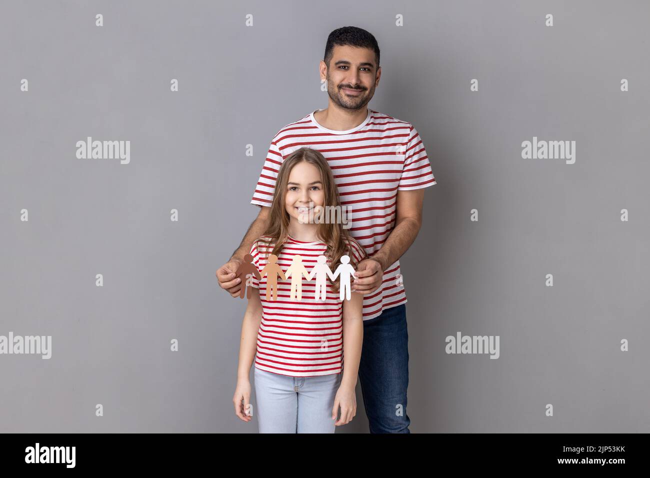 Portrait du père et de la fille en T-shirts rayés tenant la chaîne de papier. Arrêter le racisme, le message d'exclusion sociale, l'incompréhension, le déni de la société. Prise de vue en studio isolée sur fond gris. Banque D'Images