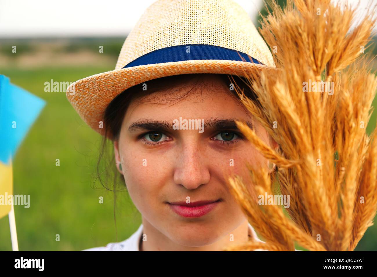 Recentrer le portrait de la jeune femme ukrainienne. Bouquet d'épillets dorés mûrs de blé attachés sur le fond de la nature du pré. Drapeau de l'Ukraine. Sourire Banque D'Images