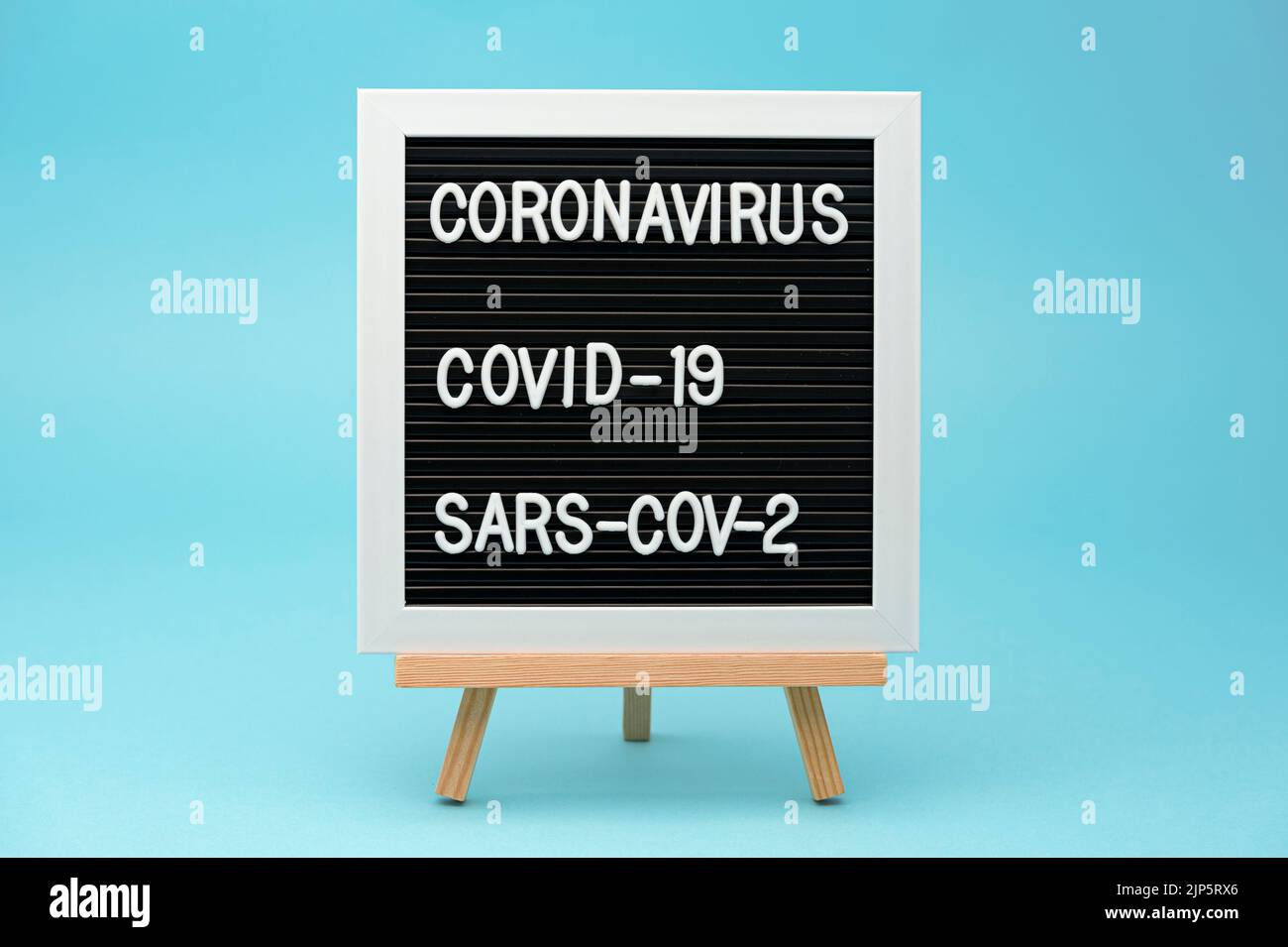 Tableau d'écriture : CORONAVIRUS, COVID-19 et SRAS-COV-2. Isolé sur fond bleu. Gros plan. Tir horizontal. Banque D'Images