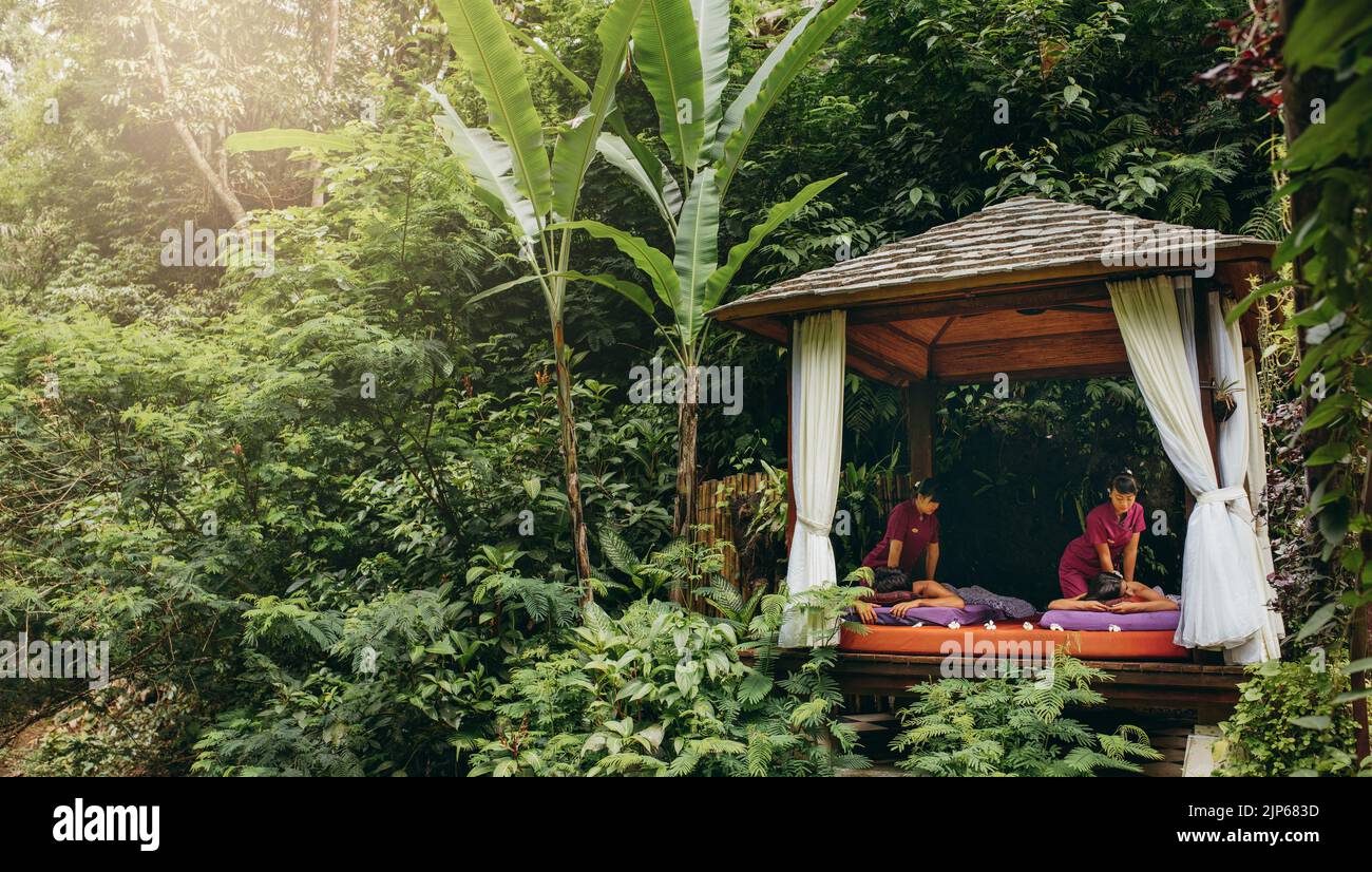 Pavillon de massage entouré d'arbres avec un couple recevant un massage corporel. Centre de spa en plein air dans le complexe de vacances. Banque D'Images