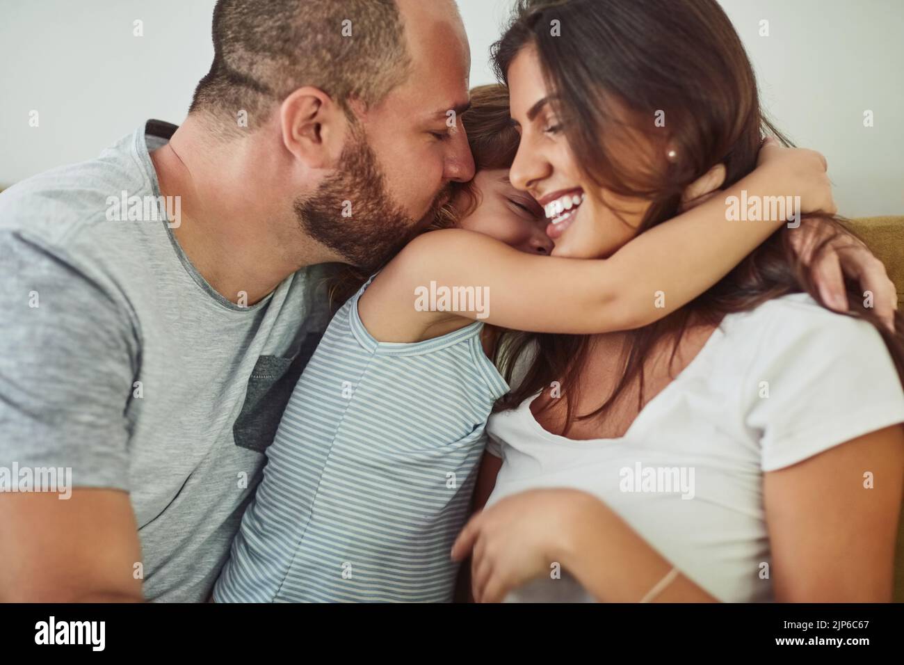 Trésor de ces moments. Une mère et un père se liant à leur adorable jeune fille à la maison. Banque D'Images