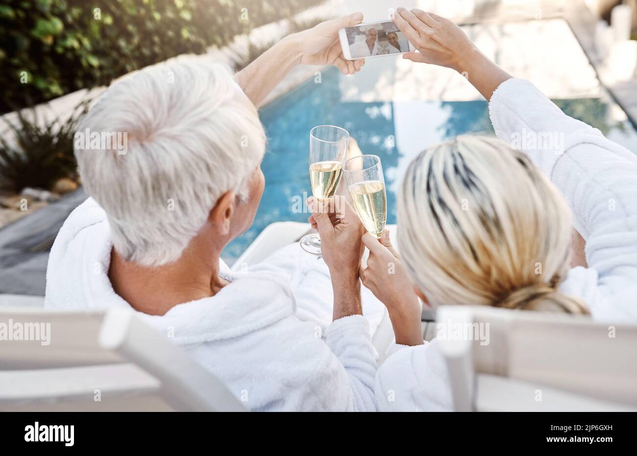 Regardez où nous sommes tout le monde. Photo d'un couple joyeux d'âge moyen ayant un toast festif avec du champagne à l'extérieur pendant la journée. Banque D'Images