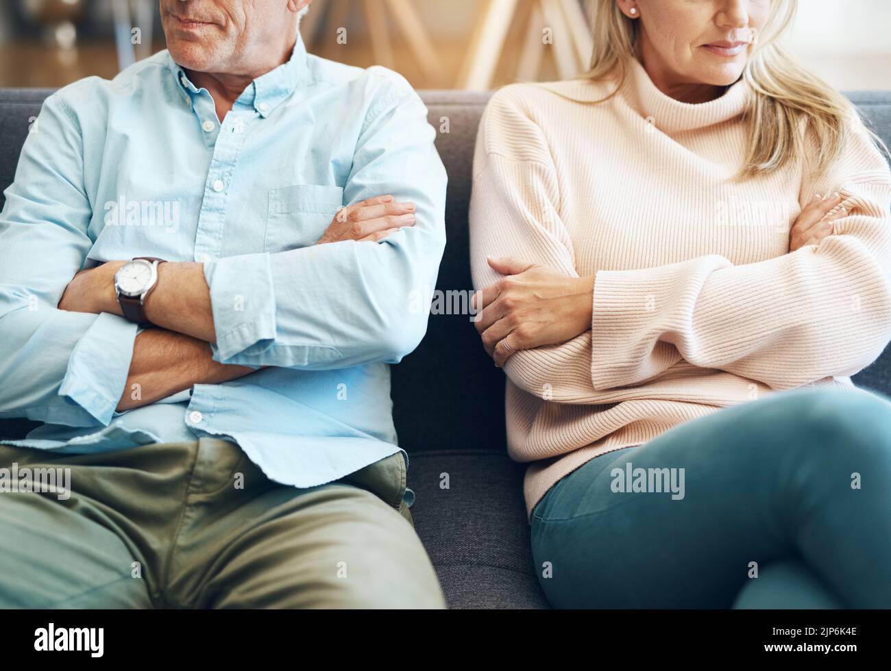 Les arguments ne sont jamais beaux. Un couple mature méconnaissable assis sur le canapé avec leurs bras repliés après un argument. Banque D'Images