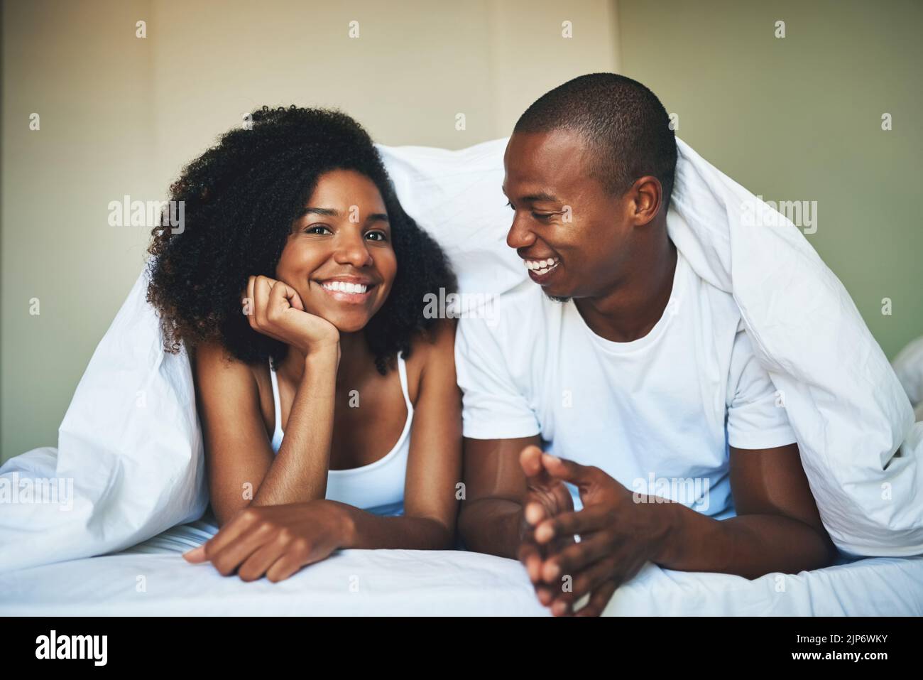 L'amour vaut la peine de se réveiller. Portrait d'un jeune couple heureux se reposant sous une couette dans leur chambre. Banque D'Images