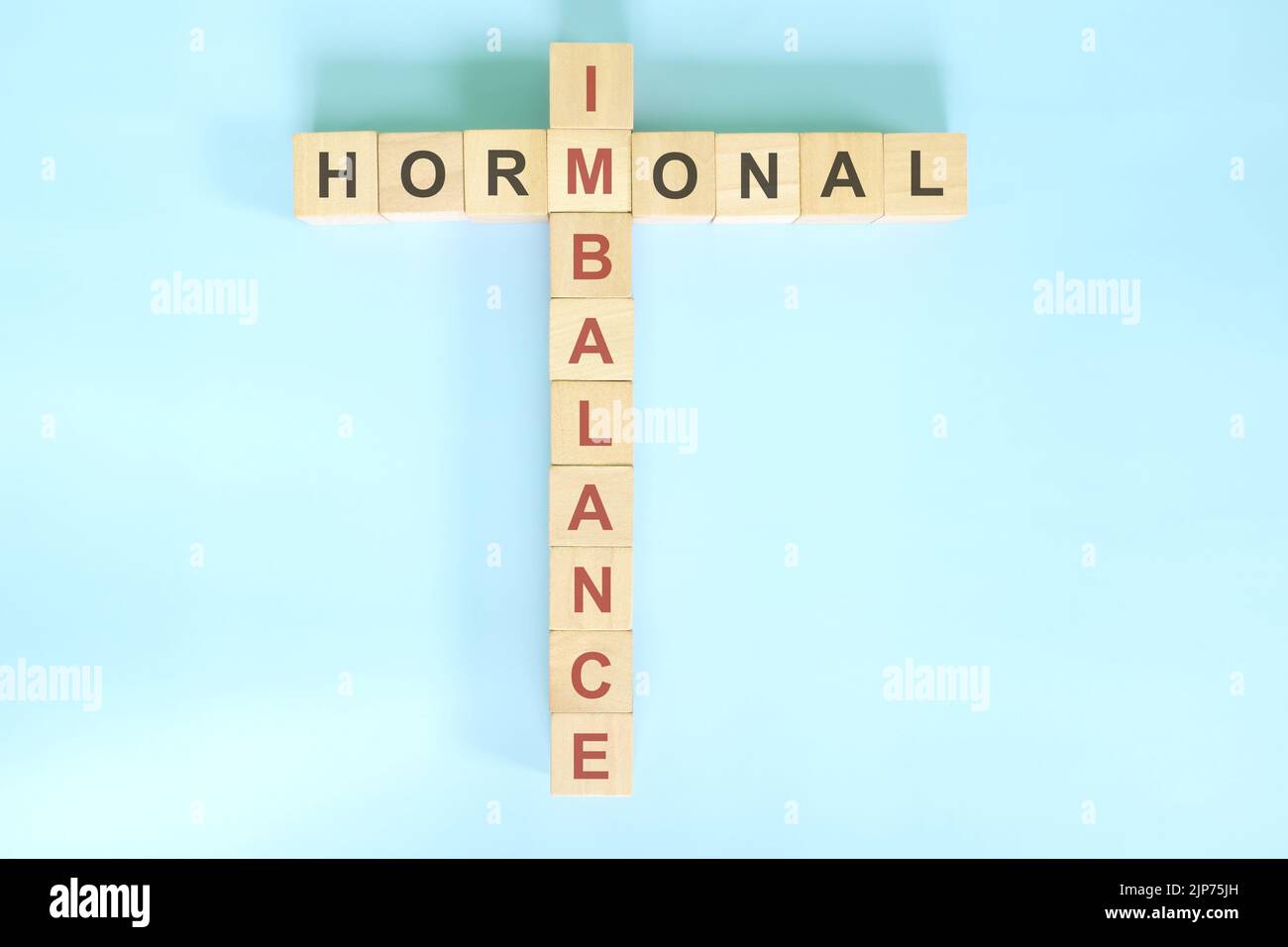 Concept de déséquilibre hormonal. Les blocs de bois crossword puzzle plat se posent dans le fond bleu. Banque D'Images
