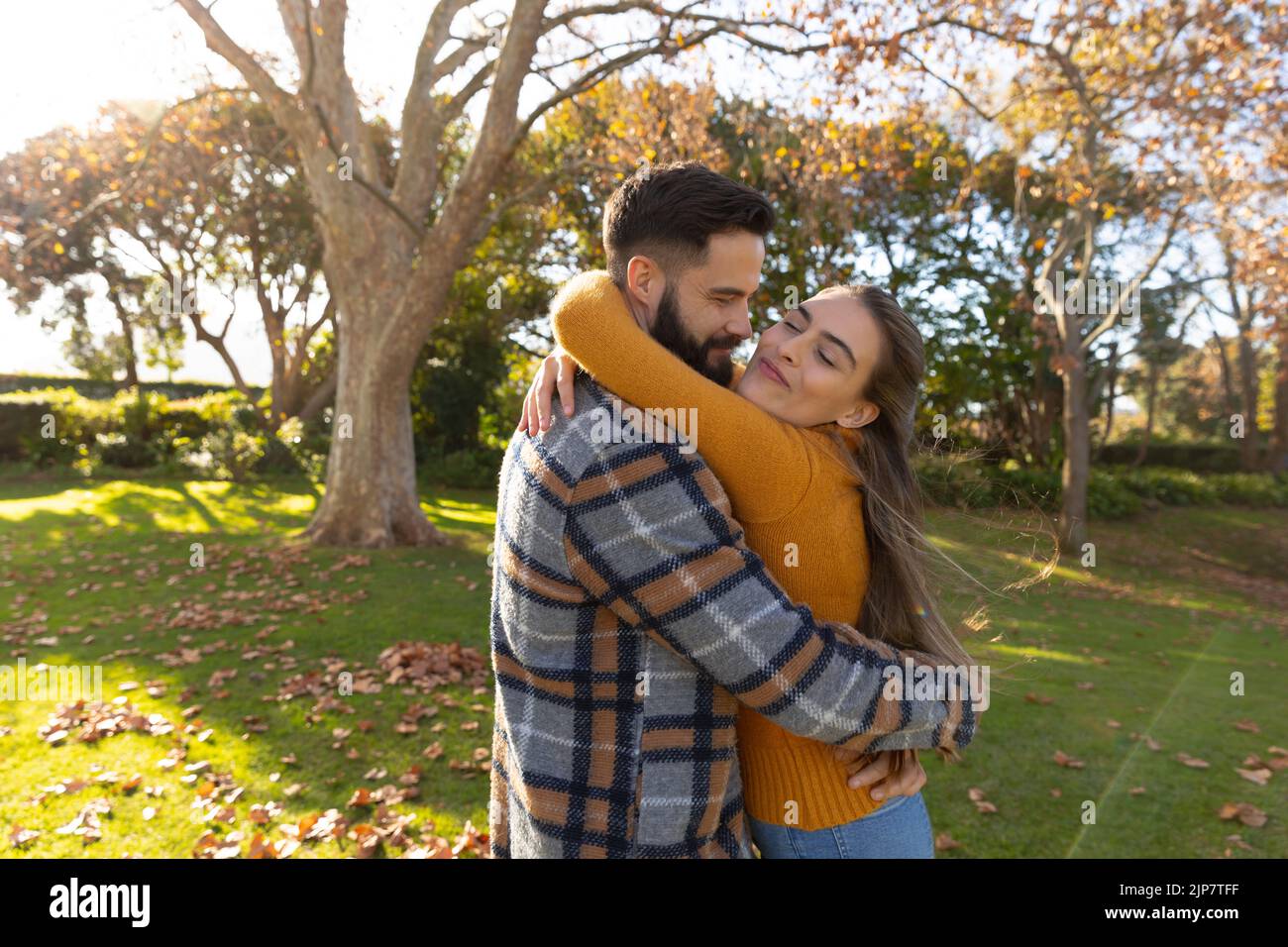 Couple caucasien heureux souriant et embrassant dans le jardin ensoleillé d'automne Banque D'Images