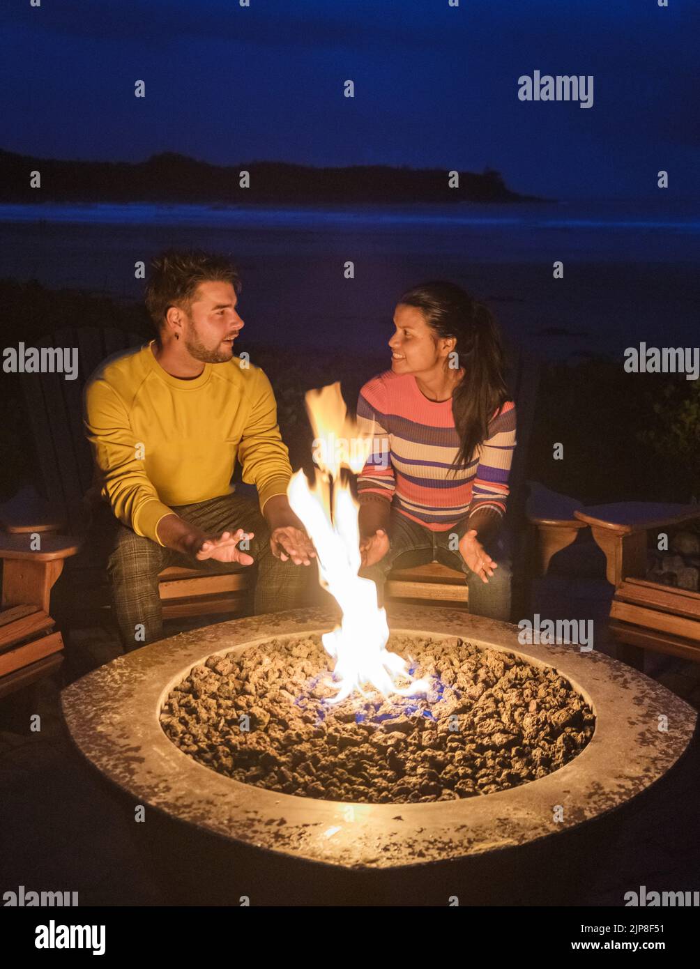 Un couple d'hommes et de femmes à mi-âge près d'un feu de camp sur la plage de Tofino Vancouver Island Canada, Banque D'Images