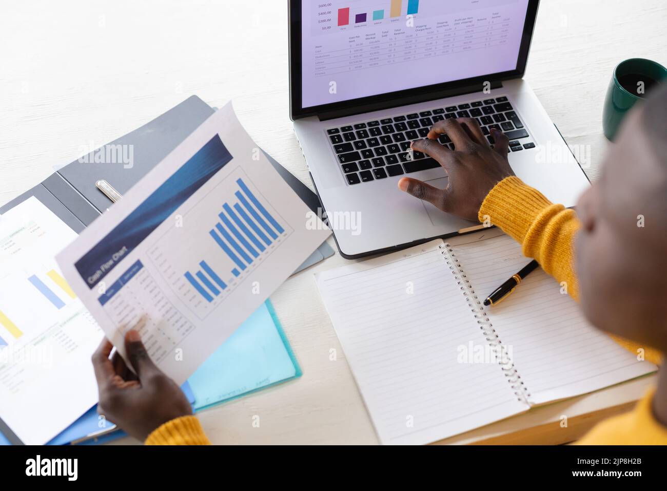 Vue d'ensemble de l'homme afro-américain utilisant un ordinateur portable et regardant des feuilles de calcul Banque D'Images