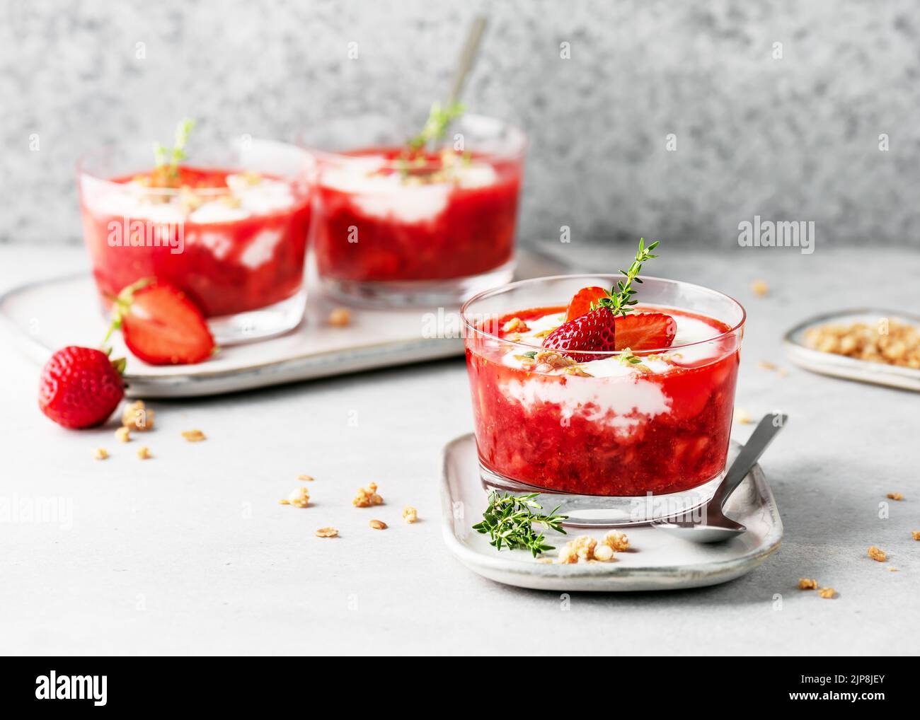 Dessert végétarien à la crème de fruits avec purée de fraises, yaourt et granola dans des bols en verre. Concept de nourriture saine et propre maison. Copier l'espace. Banque D'Images