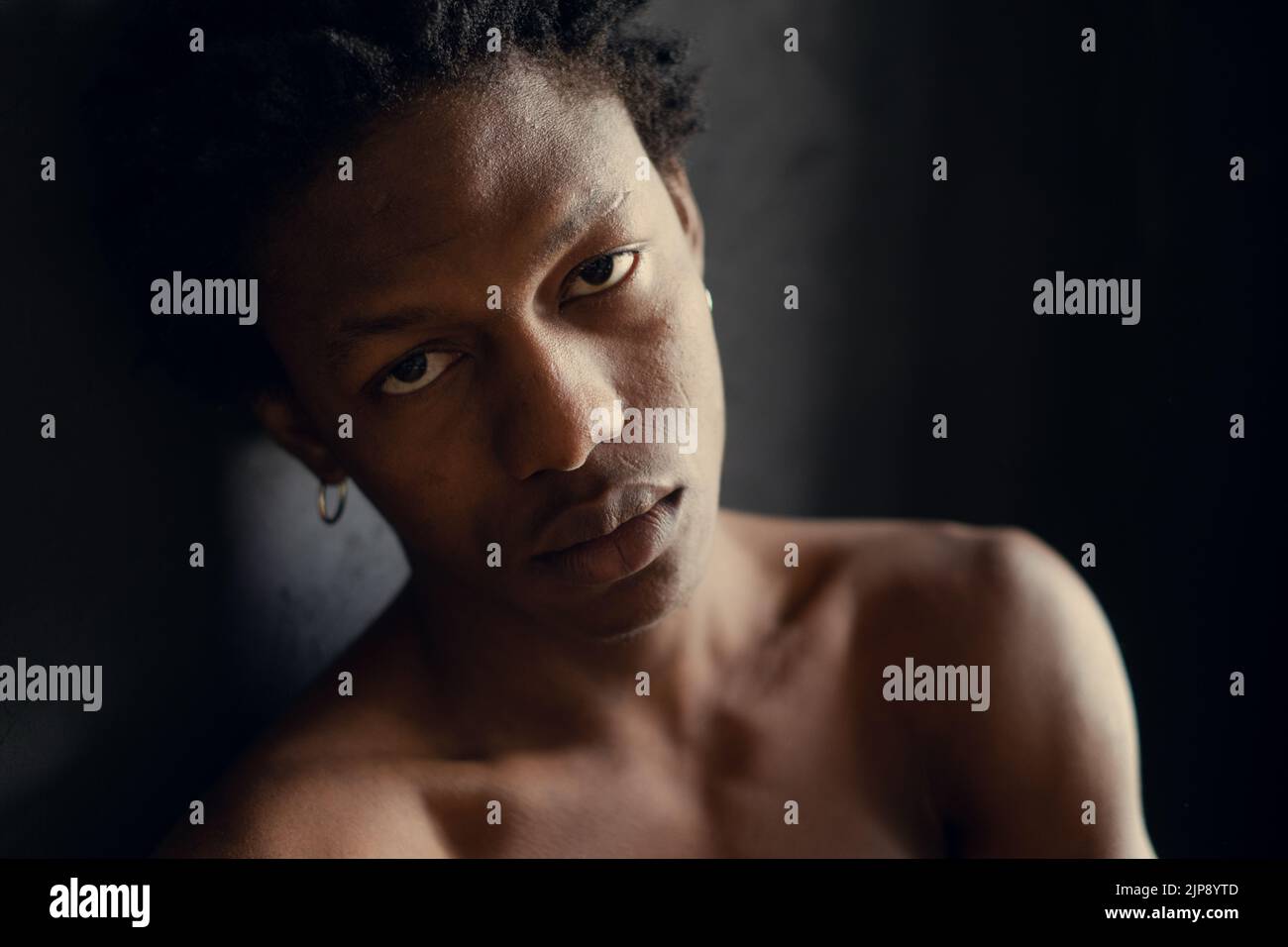 jeune africain américain avec une expression sérieuse sur fond noir. espace de copie Banque D'Images