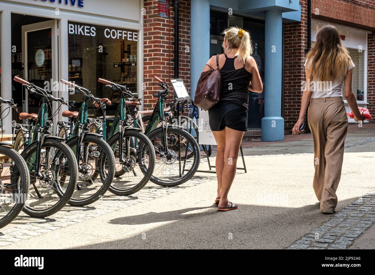 Dorking, Surrey Hills, Londres, Royaume-Uni, 14 août 2022, deux jeunes femmes marchant devant un magasin de location ou de location de vélos électroniques Banque D'Images