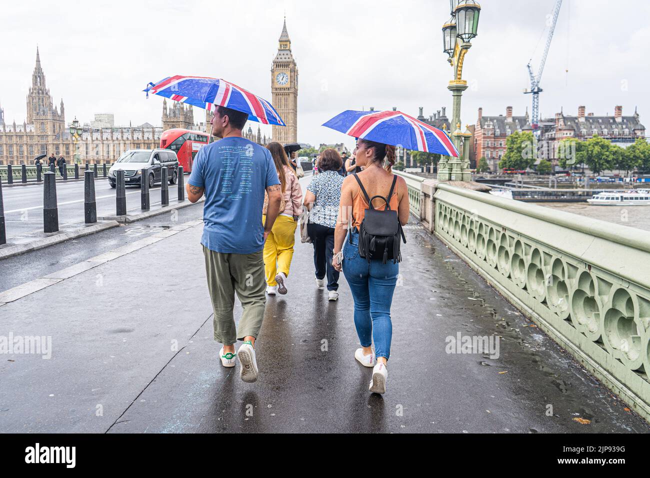 Westminster Londres, Royaume-Uni. 16 août 2022 . Les piétons marchent avec les parasols Union Jack correspondants sur le pont de Westminster pendant les averses de pluie comme la sécheresse se termine après la période sèche prolongée et l'été le plus sec en 46 ans que le bureau met émet un avertissement jaune pour les orages et les inondations flash . Credit. amer ghazzal/Alamy Live News Banque D'Images