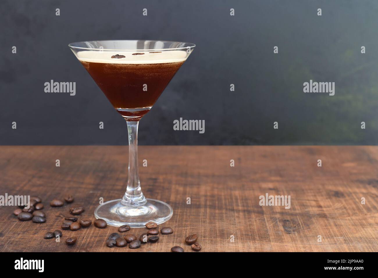 Verre de martini expresso avec grains de café sur table en bois et fond noir Banque D'Images