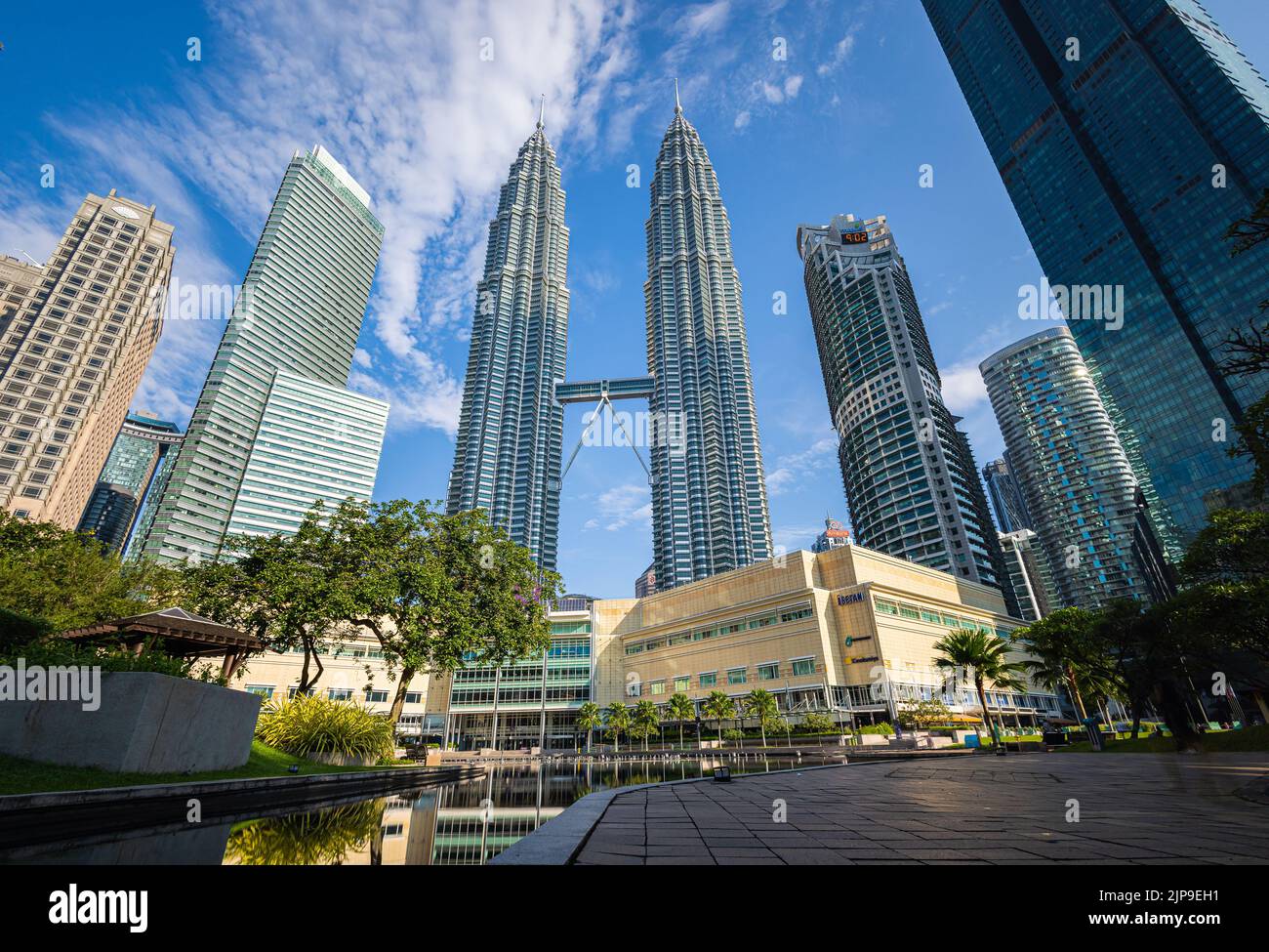 Kuala Lumpur, Malaisie - 13 août 2022 : vue sur les tours jumelles à travers les palmiers du parc KLCC. Oasis urbaine avec spectacle de fontaine. Petronas Banque D'Images