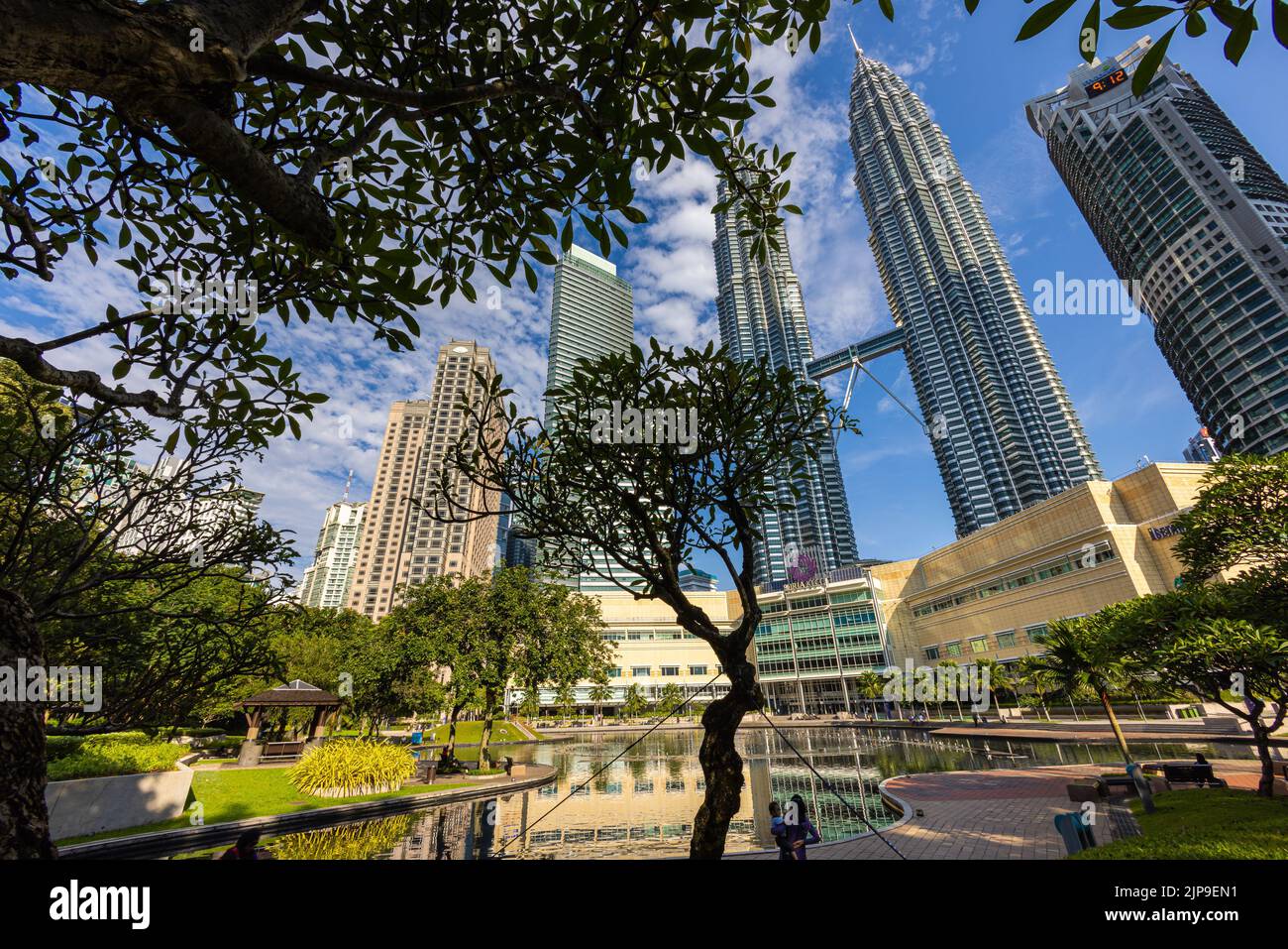 Kuala Lumpur, Malaisie - 13 août 2022 : vue sur les tours jumelles à travers les palmiers du parc KLCC. Oasis urbaine avec spectacle de fontaine. Petronas Banque D'Images