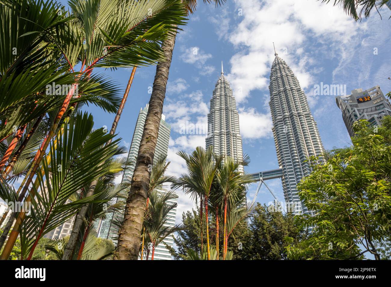 Kuala Lumpur, Malaisie - 13 août 2022 : vue sur les tours jumelles à travers les palmiers du parc KLCC. Oasis urbaine avec spectacle de fontaine. Banque D'Images