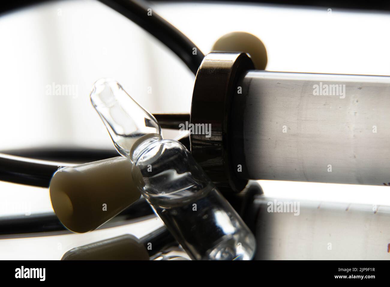 Une ampoule avec un médicament et une vieille seringue en verre et un stéthoscope se trouvent sur un miroir de près dans l'obscurité, la médecine et la santé Banque D'Images