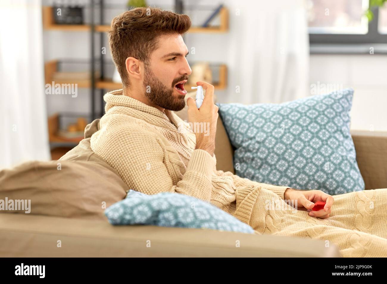 homme indien malade utilisant un spray oral à la maison Banque D'Images