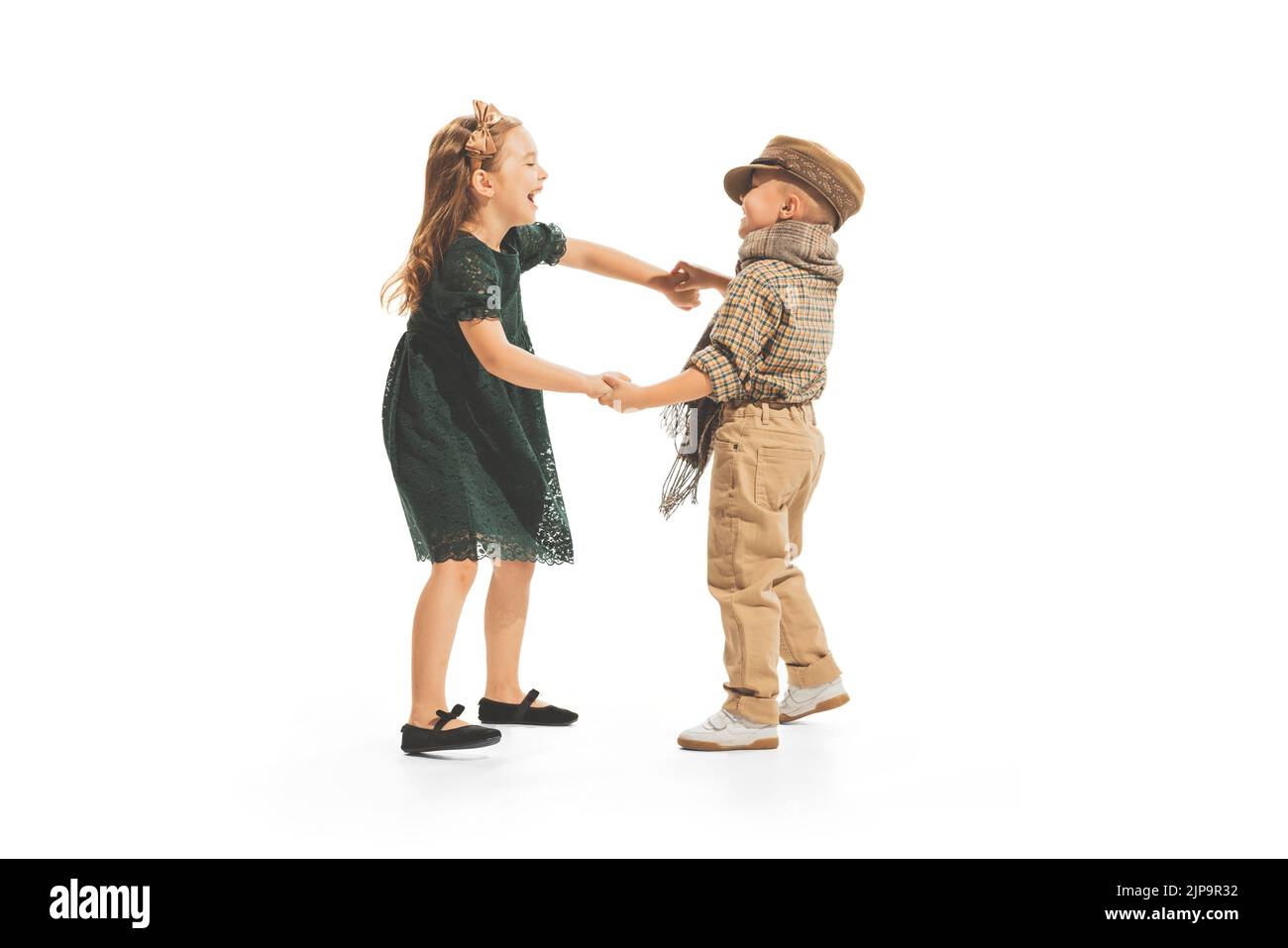 Portrait d'enfants, garçon et fille en vêtements vintage jouant ensemble, ayant le plaisir, posant isolé sur fond blanc de studio Banque D'Images