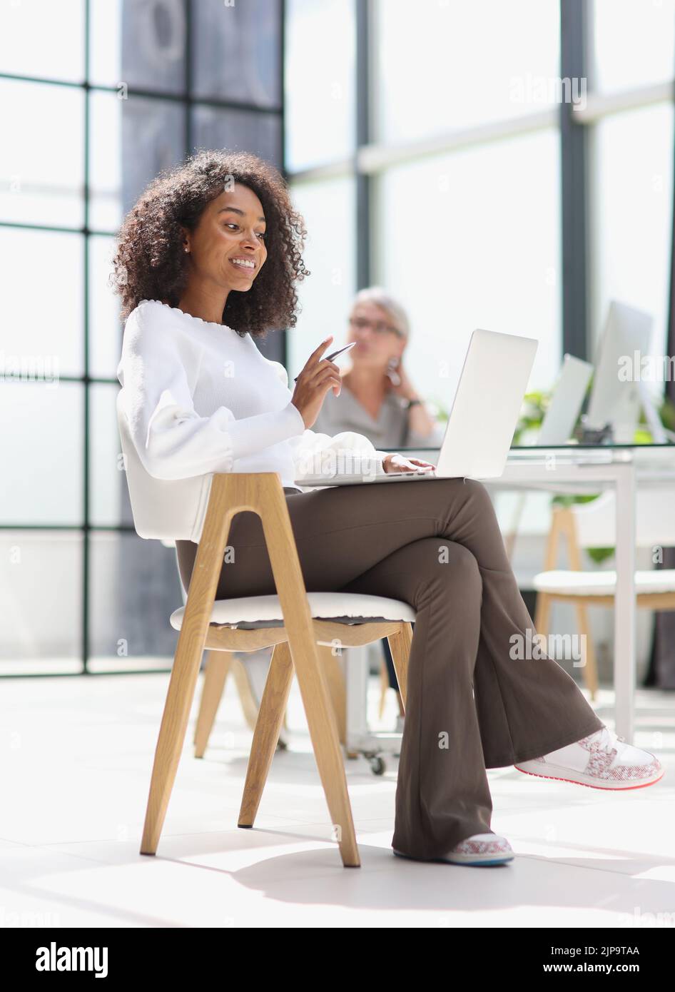 femme afro-américaine au bureau assise sur un ordinateur portable Banque D'Images