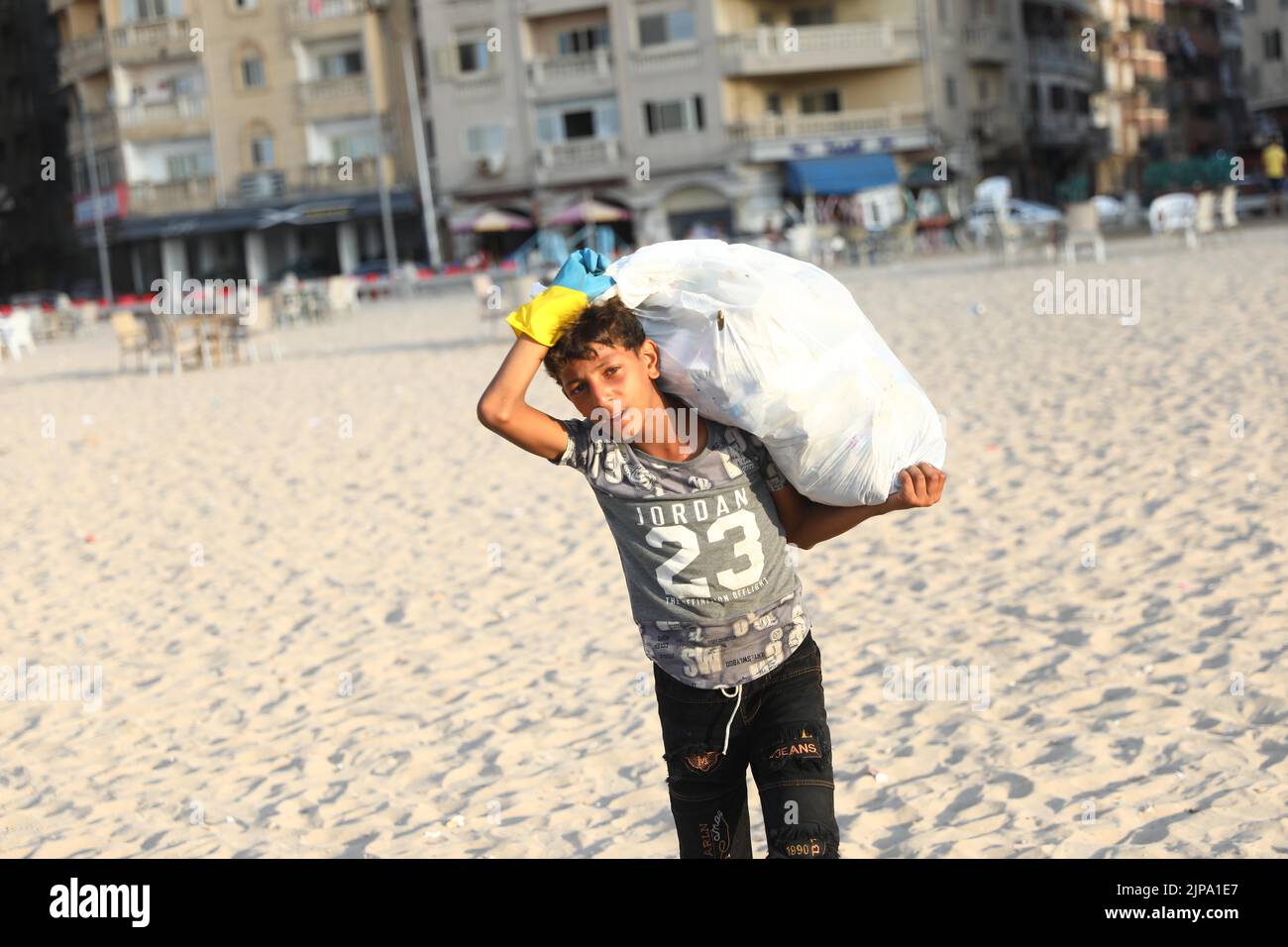 (220816) -- ALEXANDRIE, 16 août 2022 (Xinhua) -- Un enfant recueille des déchets de la plage d'Alexandrie, Égypte, 13 août 2022. Sur les plages de la ville égyptienne d'Alexandrie, un groupe de jeunes égyptiens sont généralement vus tenant des sacs en plastique vert et blanc pour recueillir les déchets de dispersion. Ils participent à une campagne de nettoyage organisée par Banlastic Egypt, un projet environnemental lancé par un groupe de jeunes de la ville méditerranéenne. Le projet vise à sensibiliser le public à la pollution par le plastique et à la façon dont les déchets de plastique à usage unique nuisent à la vie marine s'ils finissent par se terminer Banque D'Images