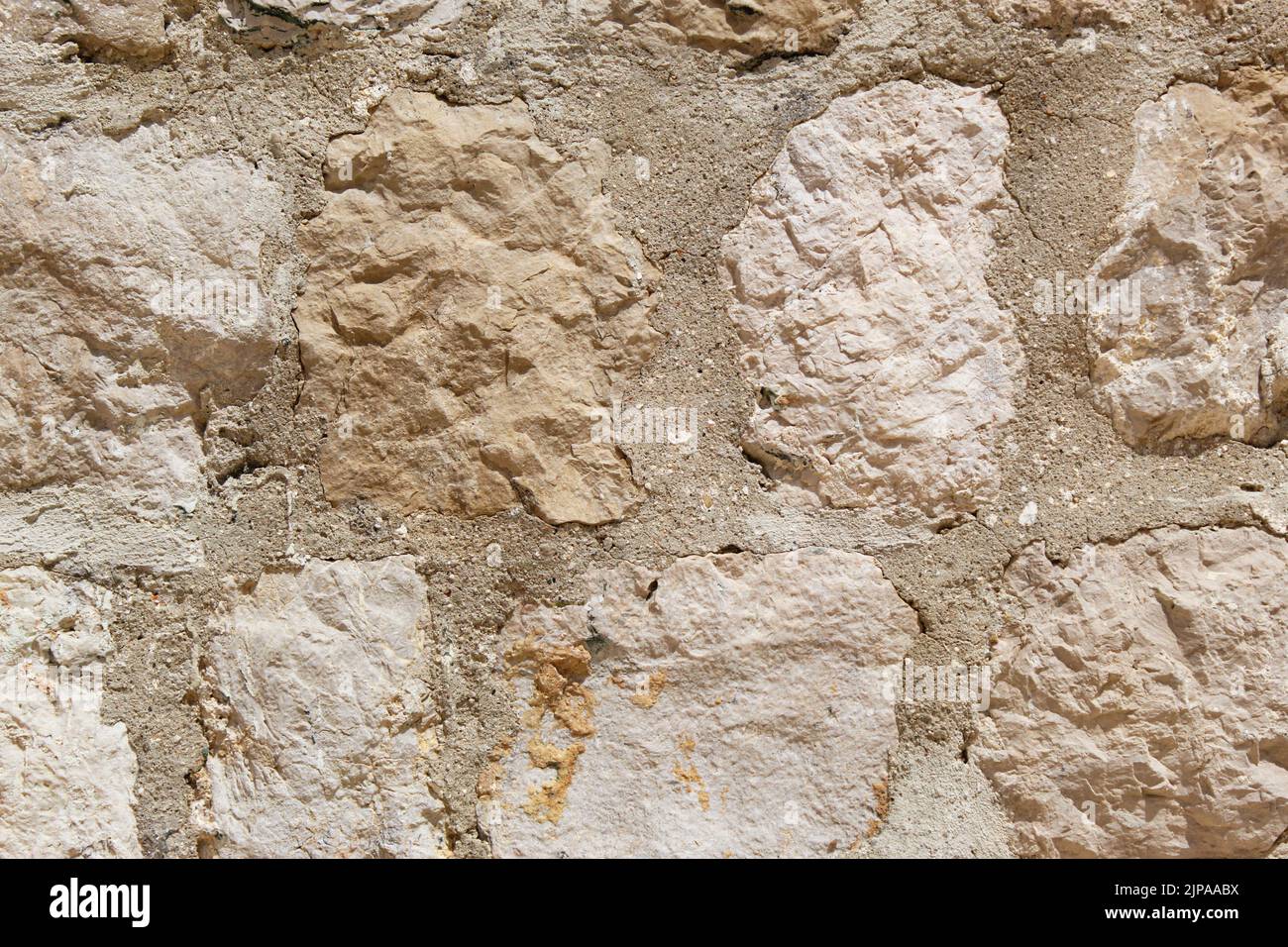 Fragment d'un mur d'une pierre ébréchée. Pavés beiges et blancs différentes tailles, arrière-plan, texture. Banque D'Images