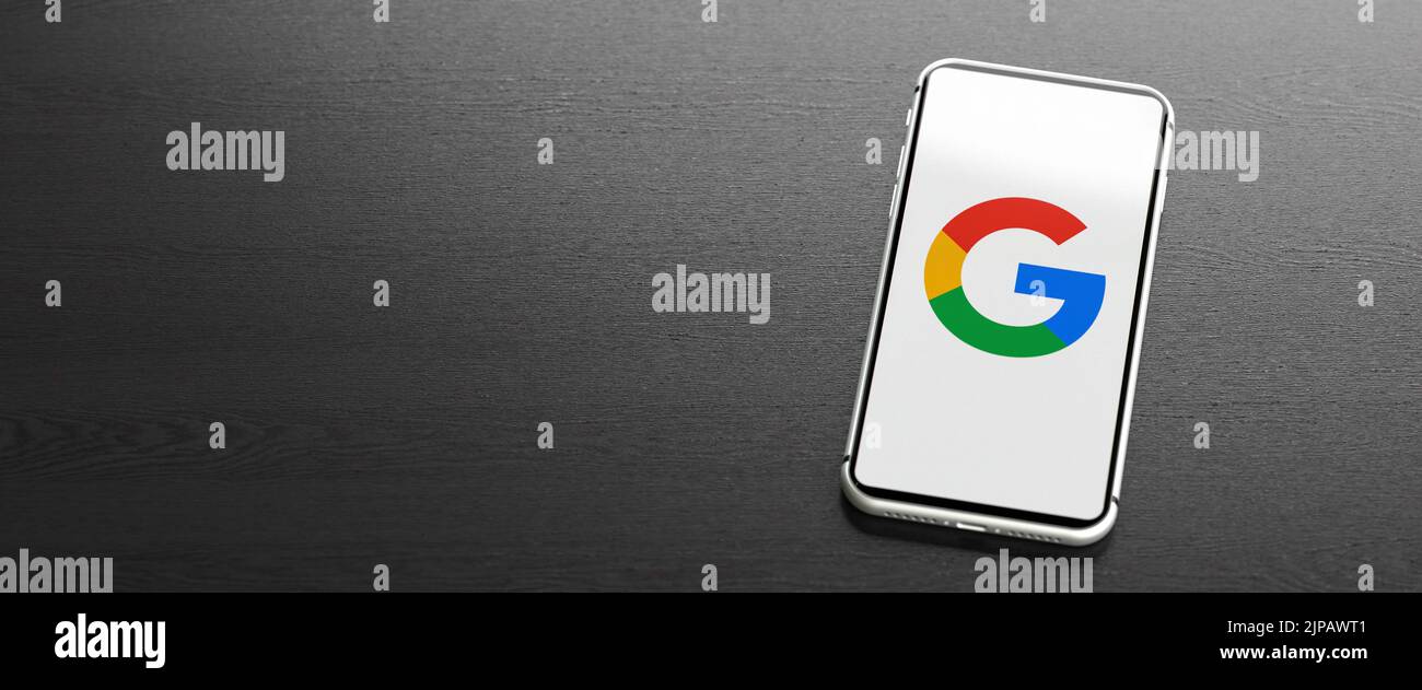 Logo de la société Google / Alphabet sur un téléphone portable sur une table. Copier l'espace. Format de bannière Web. Banque D'Images