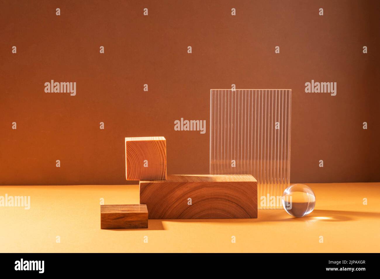 Podium abstrait créatif à partir de figures en bois et de verre, sur fond marron avec lumière dure Banque D'Images