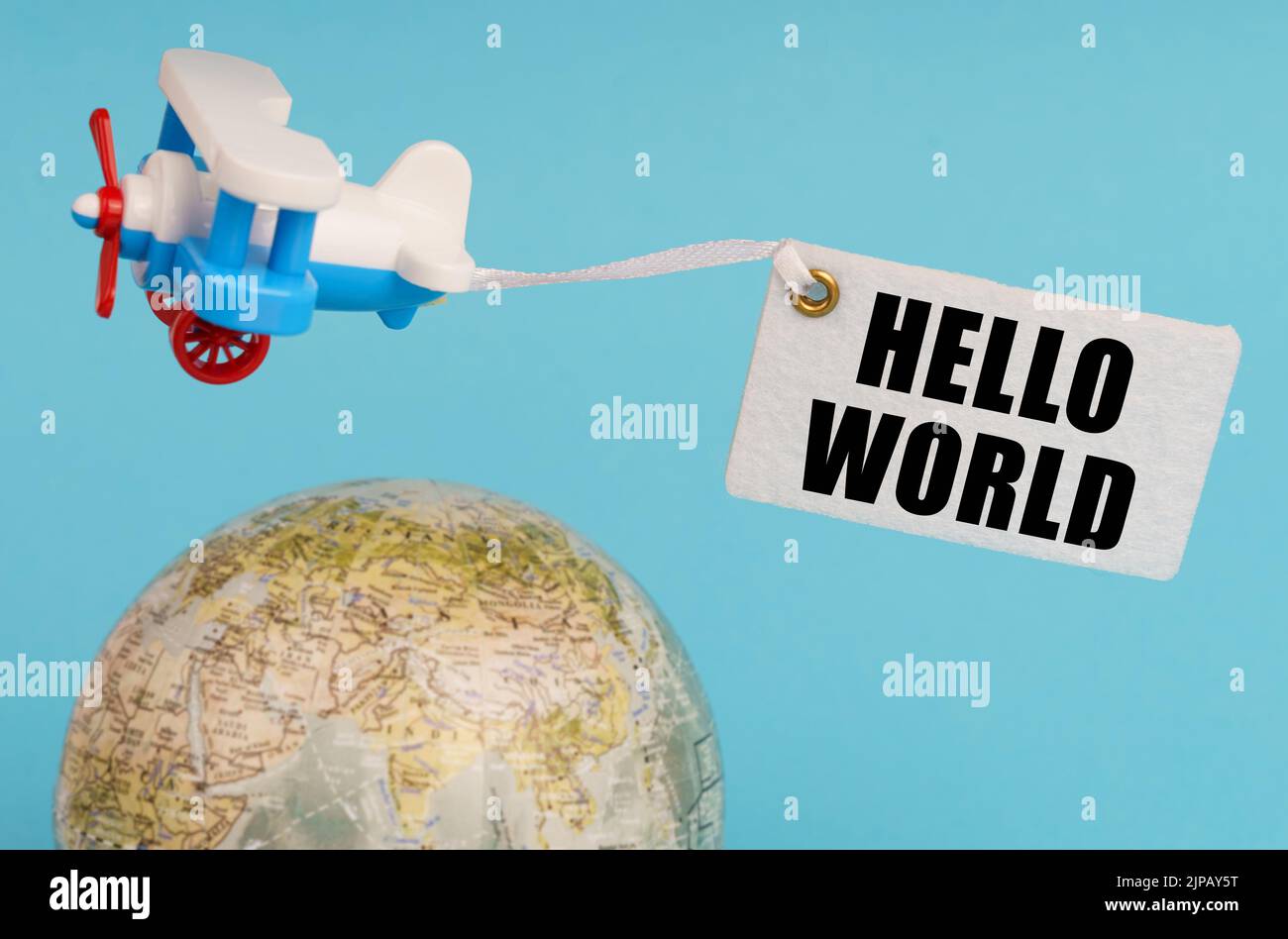 Concept de voyage et d'affaires. Sur fond bleu, un globe et un avion avec un signe - Bonjour tout le monde. Globe hors foyer. Banque D'Images