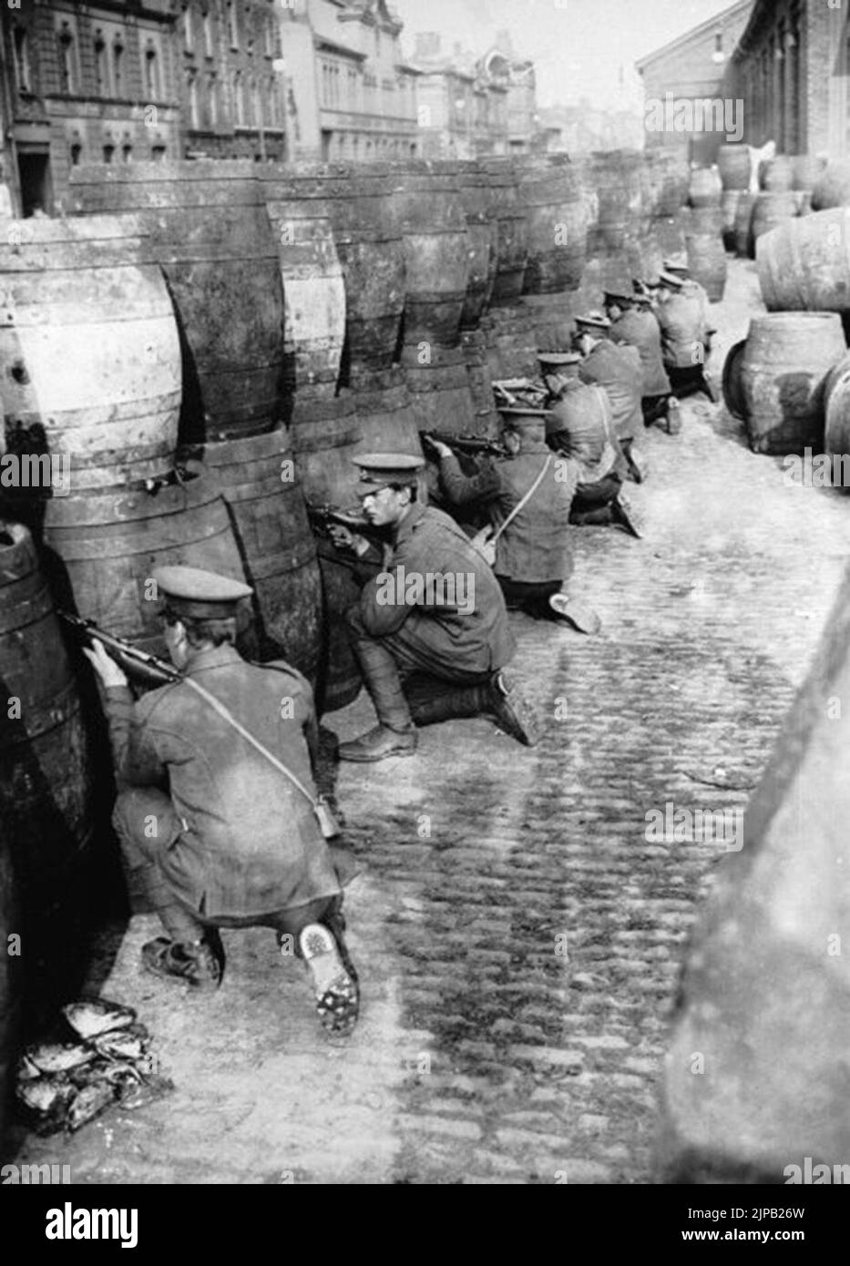 Les habitués britanniques arrachent derrière une barricade de fûts de bière vides près des quais de Dublin pendant la montée de Pâques 1916. Banque D'Images