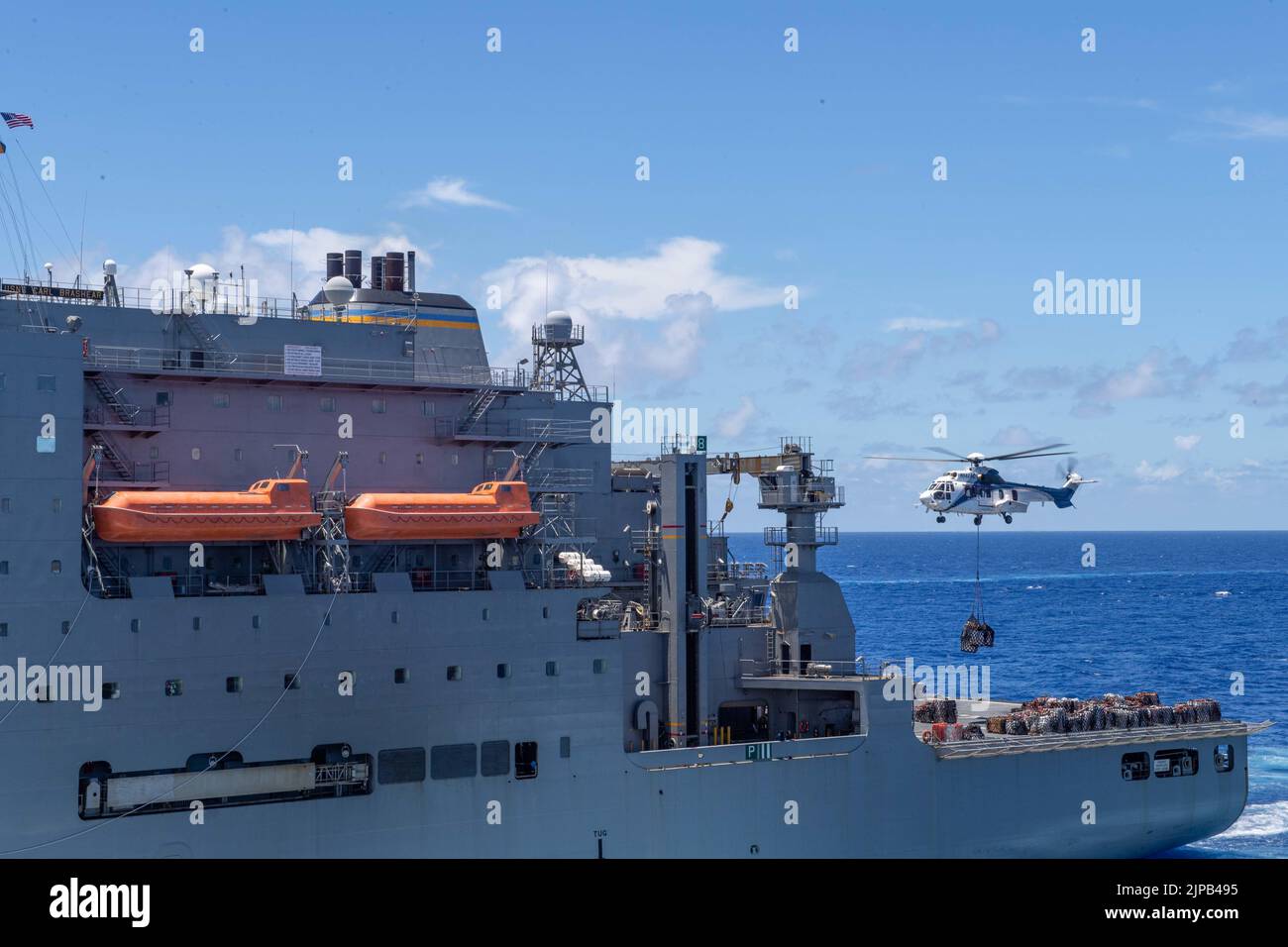 220815-N-XB010-1006 Mer des Philippines (août 15, 2022) Un hélicoptère monte avec des magasins dirigés vers le quai de transport amphibie déployé vers l'avant USS New Orleans (LPD 18) à partir du navire de fret sec USNS Carl Brashear (T-AKE 7) lors d'un réapprovisionnement en mer. La Nouvelle-Orléans, qui fait partie du Tripoli Amphiobie Ready Group, ainsi que de l'unité expéditionnaire maritime 31st, opère dans la zone de responsabilité de la flotte américaine 7th afin d'améliorer l'interopérabilité avec les alliés et les partenaires et de servir de force de réaction prête à l'emploi pour défendre la paix et la stabilité dans la région Indo-Pacifique. (É.-U. Navy photo par Mass Communicat Banque D'Images