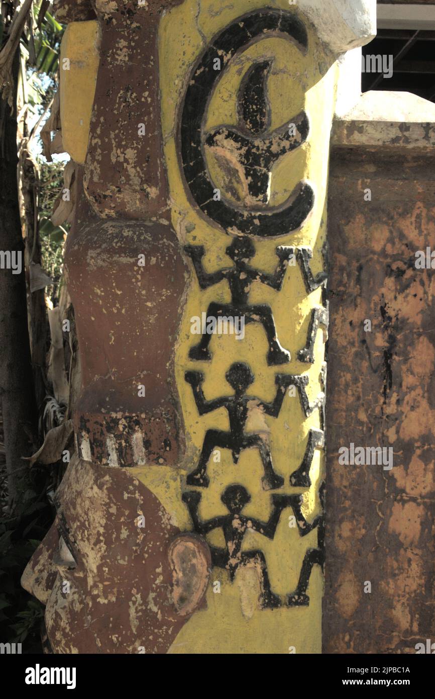 Une version moderne du relief ornemental de 'manusia kangkang' (figure humaine avec pattes à germe) est vue sur un poteau de porte devant un moulin abandonné d'huile de bois de santal à Kupang, est Nusa Tenggara, Indonésie. Banque D'Images