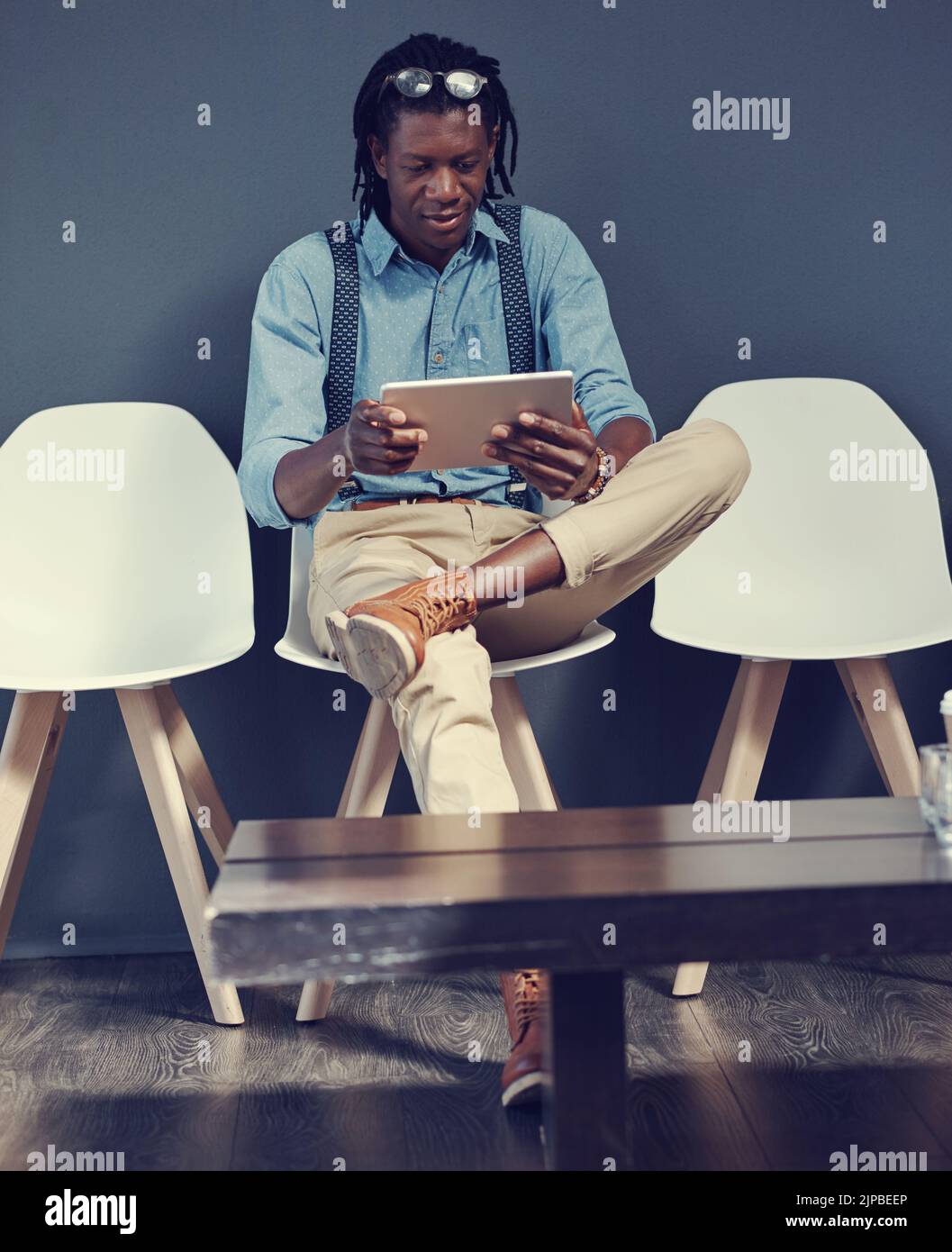 En regardant le site Web de l'entreprise. Un jeune homme d'affaires utilisant une tablette en attendant une interview. Banque D'Images