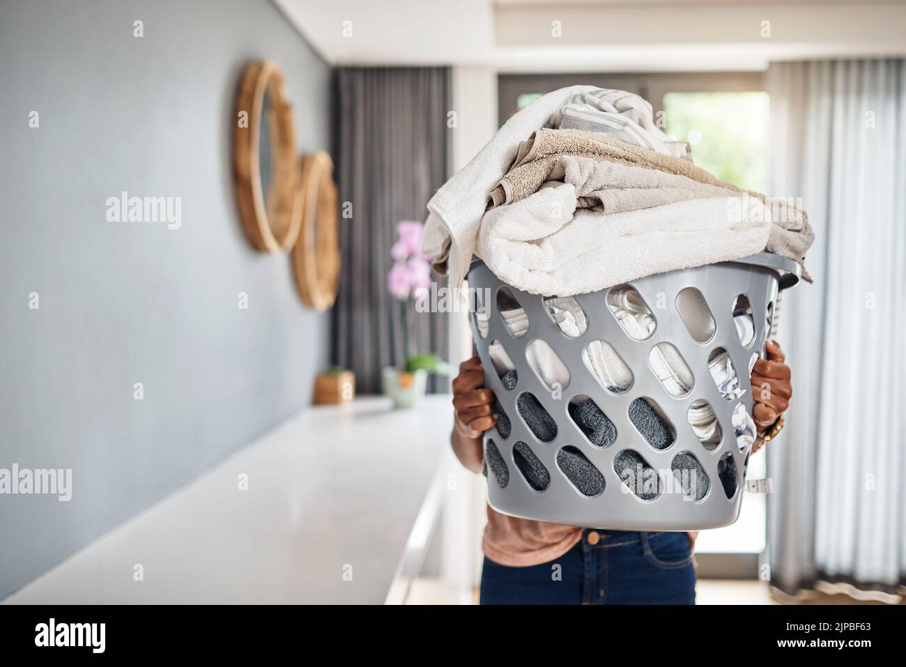 C'est ma chose la moins préférée à faire. Une femme portant un panier à linge plein de lavage à la maison. Banque D'Images