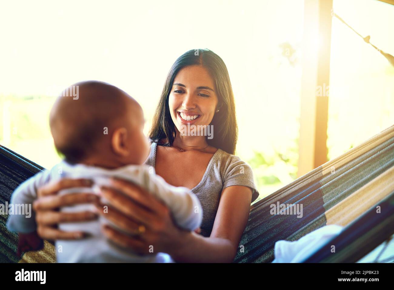 Vous avez l'air plus comme votre mère. Une jeune mère gaie tenant son bébé fils tout en lui souriant dehors à la maison. Banque D'Images