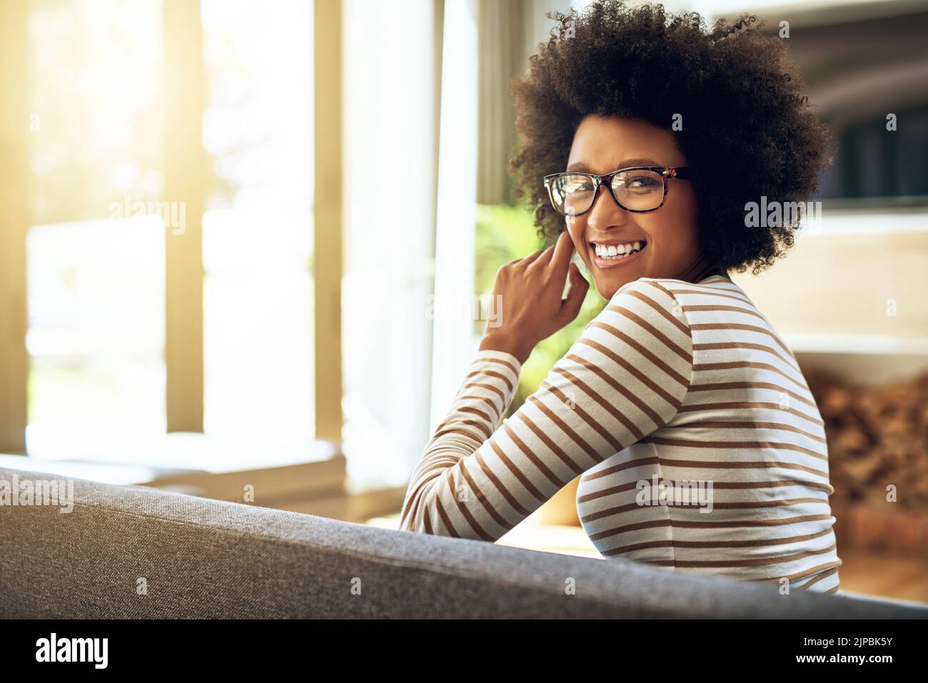 C'est facile et agréable aujourd'hui. Portrait d'une jeune femme joyeuse assise confortablement sur un canapé à la maison pendant la journée. Banque D'Images