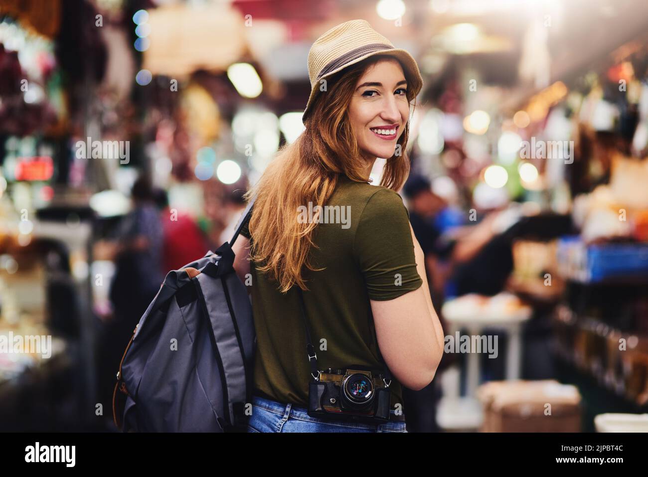 Comment puis-je regarder. Une jeune femme joyeuse marchant dans un marché très occupé dehors pendant la journée. Banque D'Images