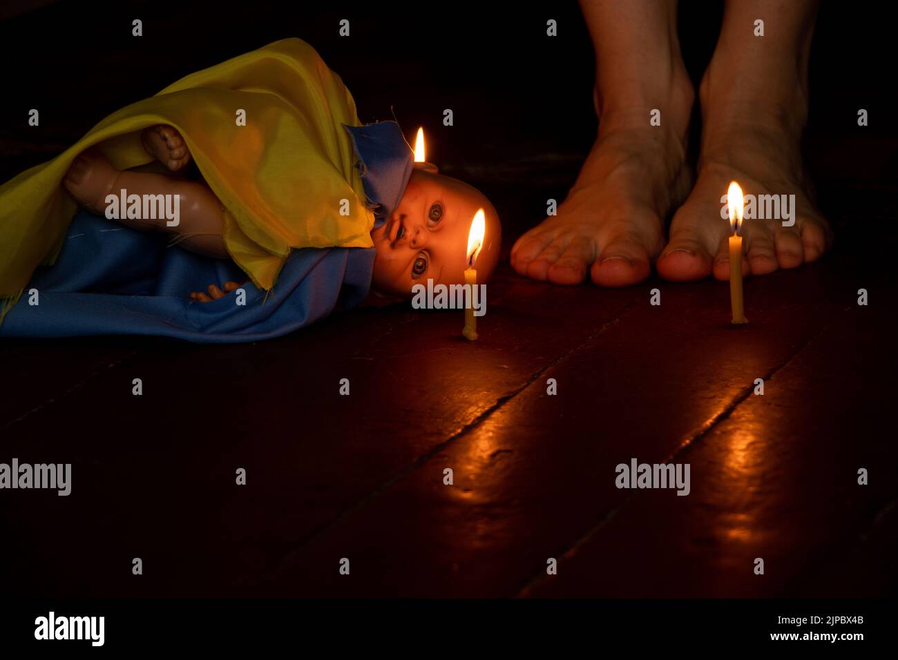 Une poupée d'enfants avec le drapeau de l'Ukraine se trouve sur le sol de la maison dans l'obscurité et à côté des jambes de la fille, la guerre en Ukraine, la mort de ch Banque D'Images
