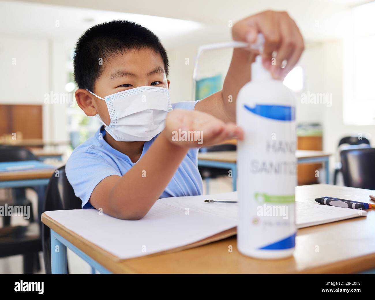Hygiène, sécurité et routine de covid d'un petit garçon utilisant l'assainisseur pour les mains à l'école. Jeune étudiant asiatique avec un masque pratiquant la bonne santé par le nettoyage Banque D'Images