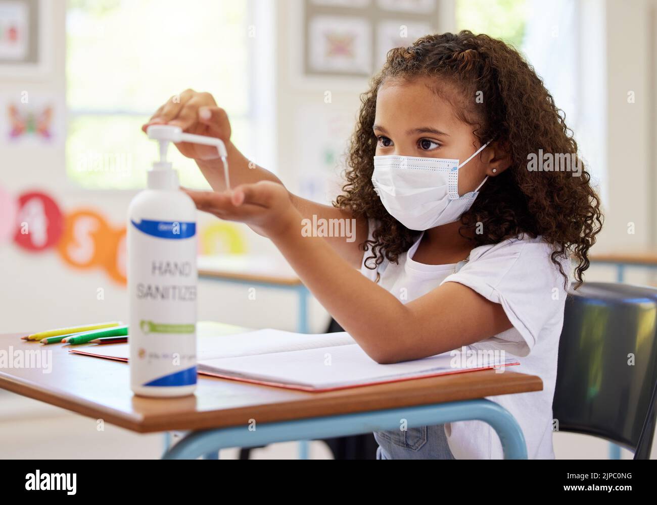 .... Enfant de l'école utilisant un désinfectant pour les mains pour la protection des germes, l'hygiène et la désinfection pendant les règlements du protocole Covid dans une salle de classe. Jeune étudiant Banque D'Images